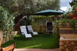 un gruppo di sedie e un ombrellone in un cortile di Villa in Antico Baglio a Castellammare del Golfo