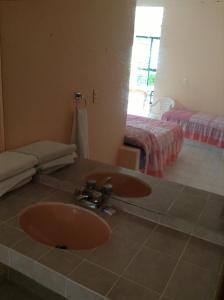 une salle de bains avec lavabo et une chambre avec 2 lits dans l'établissement Hotel Tecozautla, à Tecozautla