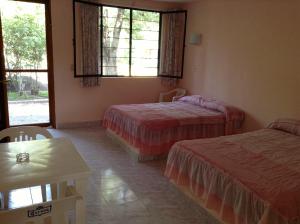 Cette chambre comprend 2 lits, une table et des fenêtres. dans l'établissement Hotel Tecozautla, à Tecozautla