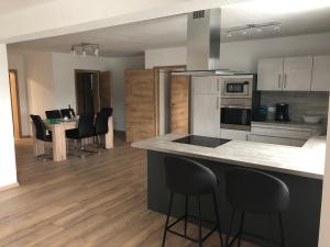 a kitchen with a counter with chairs and a table at Landhaus Ferienwohnungen mit Pool und Wellness in Neukirchen-Balbini