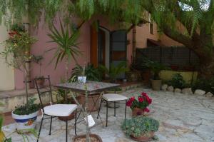 un patio con tavolo, sedie e piante in vaso di Villa in Antico Baglio a Castellammare del Golfo