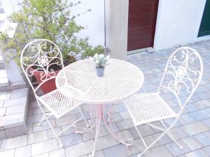 een witte tafel en twee stoelen met een potplant bij Family house Bacalja in Preko