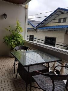 une table et des chaises en verre sur un balcon avec une fenêtre dans l'établissement BaanBusarin Hotel, à Hua Hin