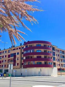 un gran edificio de apartamentos con un árbol aakura delante de él en VUT sencilla y cómoda en Ávila capital., en Ávila