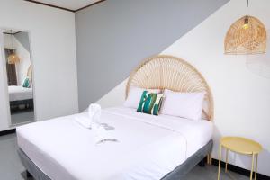 um quarto com uma cama branca e um banco amarelo em Rarem Bed & Breakfast em Bandar Lampung