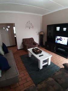 a living room with a white coffee table and a tv at Roos Getaway Apartments #8 in Bela-Bela