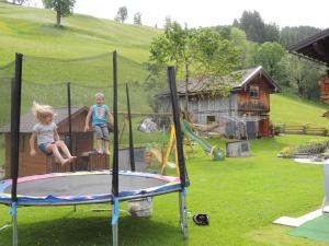 zwei Kinder spielen auf einem Trampolin im Hof in der Unterkunft Haus Bergfried in Filzmoos