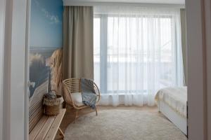 a bedroom with a bed and a chair and a window at Apartament Zefir Mechelinki in Mechelinki