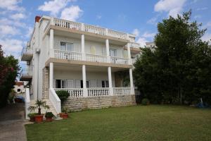 a large white building with a balcony and a yard at Apartment and Rooms Villa Kolonada in Vodice
