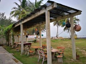 a picnic shelter with tables and chairs in a field at ALA Beach Lodge - Markisa Homestay in Bachok