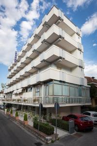 duży biały budynek z samochodami zaparkowanymi przed nim w obiekcie Hotel Tre Assi w Rimini