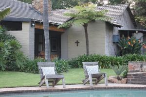 two chairs by a pool in front of a house at Green Pascua Bed and Breakfast in Roodepoort