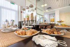 a buffet with several plates of pastries on a table at B&B HOTEL Park Hotel Cassano in Cassano dʼAdda