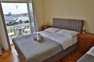 a bedroom with a bed with a teddy bear on it at Apartment and Rooms Villa Kolonada in Vodice