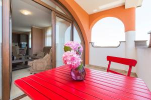 a red table with a vase of flowers on it at Penthouse Aurora in Manjadvorci
