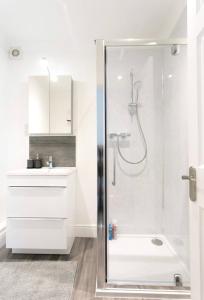 a white bathroom with a shower and a sink at Ammonite Luxury beachfront apartment in Lyme Regis