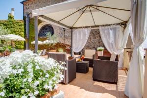 a patio with chairs and an umbrella and flowers at Hotel San Lino in Volterra