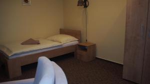 a small bedroom with a bed and a chair at Hotel Slnecny Dvor in Michalovce