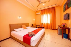 a bedroom with a bed with a red and white blanket at D’ Village Cottage in Pantai Cenang