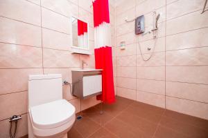 a bathroom with a toilet and a shower and red curtains at D’ Village Cottage in Pantai Cenang