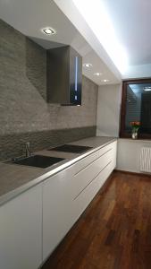 kuchnia z białymi szafkami, umywalką i oknem w obiekcie Quiet and spacious apartment with garage option w Krakowie