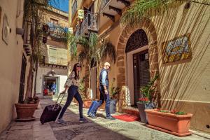 a man and woman walking down a street with luggage at Garibaldi Relais in Sciacca