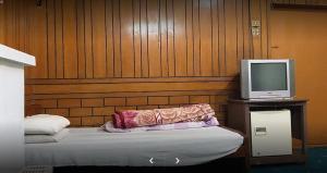 um quarto com uma cama e uma televisão numa mesa em Lourdes Hotel em Quetta