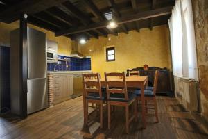 Una cocina con mesa y sillas y un refrigerador. en El Patio de Fuenteuso, en Villosilla de la Vega