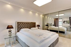 a large white bedroom with a large bed and a mirror at Old Town Apartments Apartinfo in Gdańsk