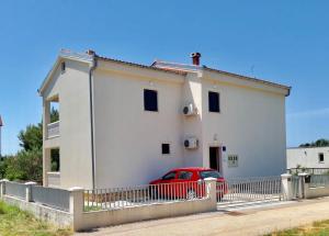 a white house with a red car parked in front of it at Apartment Pepa Starigrad Paklenica in Starigrad