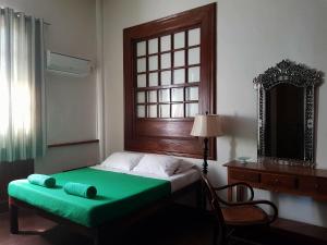 a bedroom with a green bed with a window and a mirror at Casa Tentay in Iloilo City