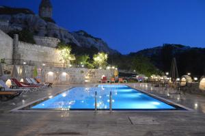 una piscina por la noche con montañas en el fondo en Grand Elite Cave Suites en Goreme