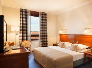 a hotel room with a bed and a desk and a window at Best Western Premier Hotel Astoria in Zagreb