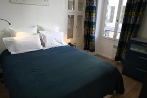 a bedroom with a blue bed with white pillows and a window at la terrasse in Nice