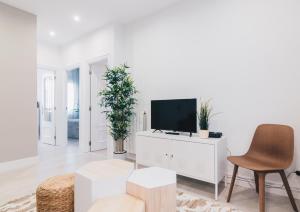 ein weißes Wohnzimmer mit einem TV und einem Stuhl in der Unterkunft Altair apartment by People Rentals in Bilbao
