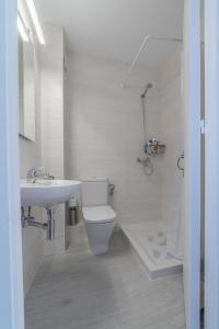 a white bathroom with a toilet and a sink at Vistas al mar y la piscina in Arenal d'en Castell