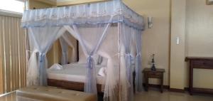 a bedroom with a canopy bed with a bench at Happy Ripples Beach Resort in Mabilao