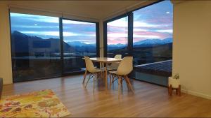mesa y sillas en una habitación con ventana grande en Ridge View en Wanaka