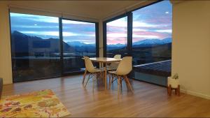 a table and chairs in a room with a large window at Ridge View in Wanaka
