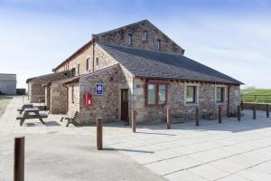 un pequeño edificio de piedra con una mesa de picnic delante de él en Pattys Farm Barn, en Cockerham