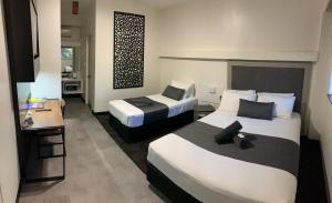 ein Hotelzimmer mit 2 Betten und einem Tisch in der Unterkunft The Stuart Hotel-Motel in Katherine