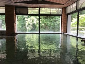Nikko Nationalpark Kawamata Onsen KURA في نيكو: غرفة فارغة مع تجمع مياه مع نوافذ كبيرة