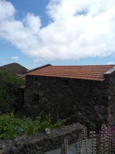 una casa de piedra con techo rojo en Casa Rural Higuera Morales, en Mocanal