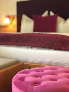 a bed with a pink ottoman in a bedroom at Hotel Garni Landhaus Florian in Bad Blumau