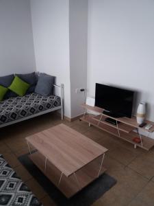 uma sala de estar com um sofá e uma televisão de ecrã plano em Ellie's em Kardamaina