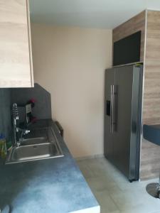 a kitchen with a sink and a stainless steel refrigerator at Aub Ptit Confort in Dienville