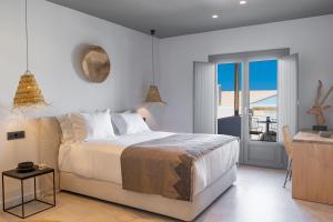 a white bedroom with a bed and a balcony at Lemon Suites Santorini in Fira