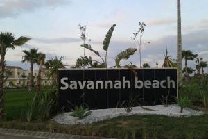 een bord voor het strand van Savannah met palmbomen op de achtergrond bij Magnifique Villa a Savannah Beach in Sidi Rahal