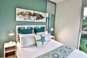 a bedroom with a white bed and a painting on the wall at 207 La Ballito-Luxury Family apartment in Ballito +24 photos
