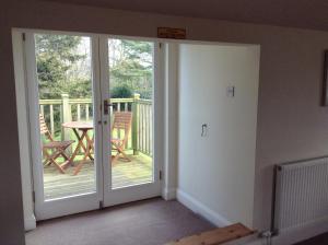 a room with a door leading to a deck with a table at The Garden Loft in Freethorpe